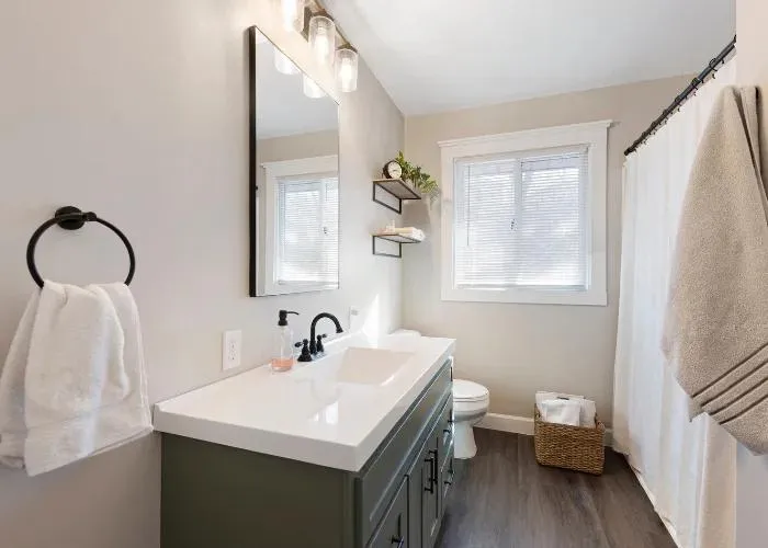 Bathroom featuring a large mirror, white vanity, and contemporary shower stall with glass enclosure.