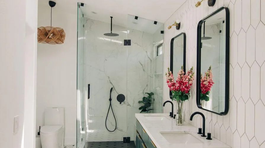 Bathroom featuring a glass enclosed shower, dual sinks, and contemporary finishes.