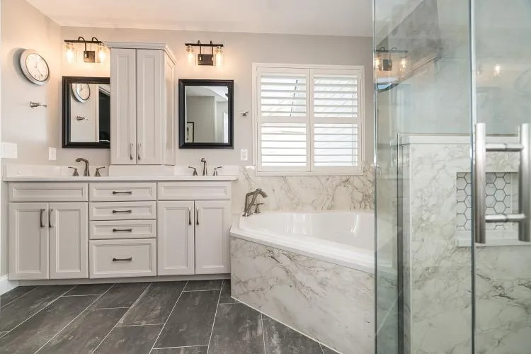 Bathroom renovation showcasing contemporary design elements such as marble countertops, sleek cabinetry, and large format tiles.