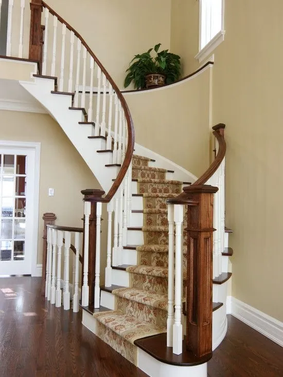 Wooden staircase with hardwood treads and risers, including a curved handrail and a runner.
