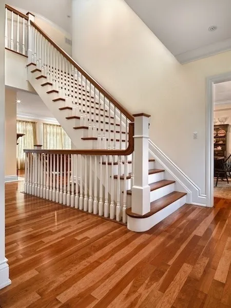 White spindle staircase with hardwood treads and a runner.