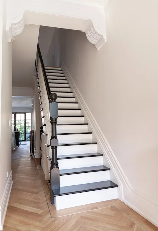 Black railing on hardwood stairs with white risers.