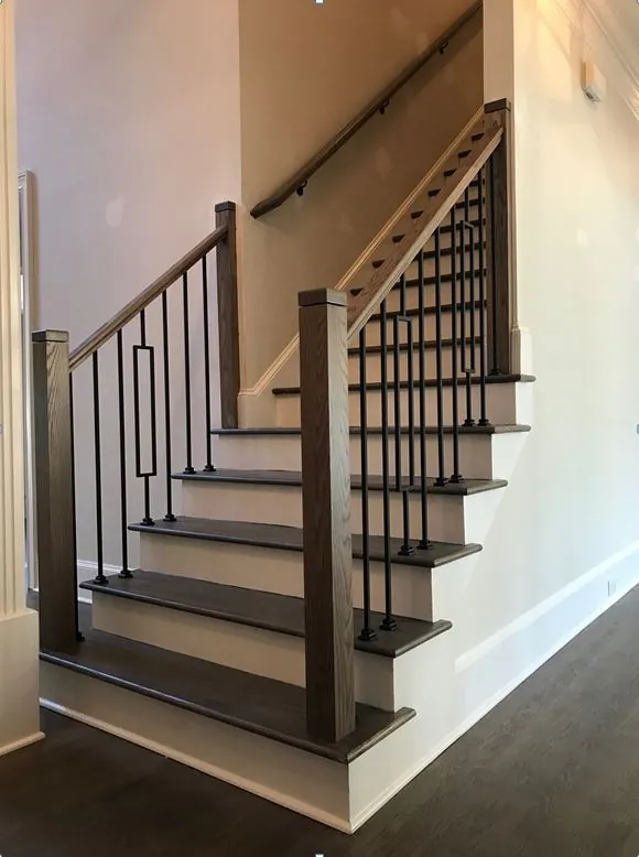 Black metal posts and balusters on wooden staircase railing.