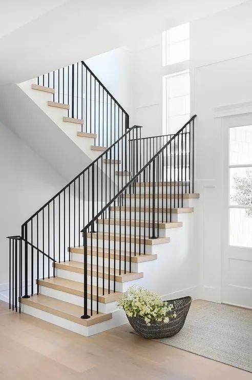 Staircase with black railing and spindles, white runner.